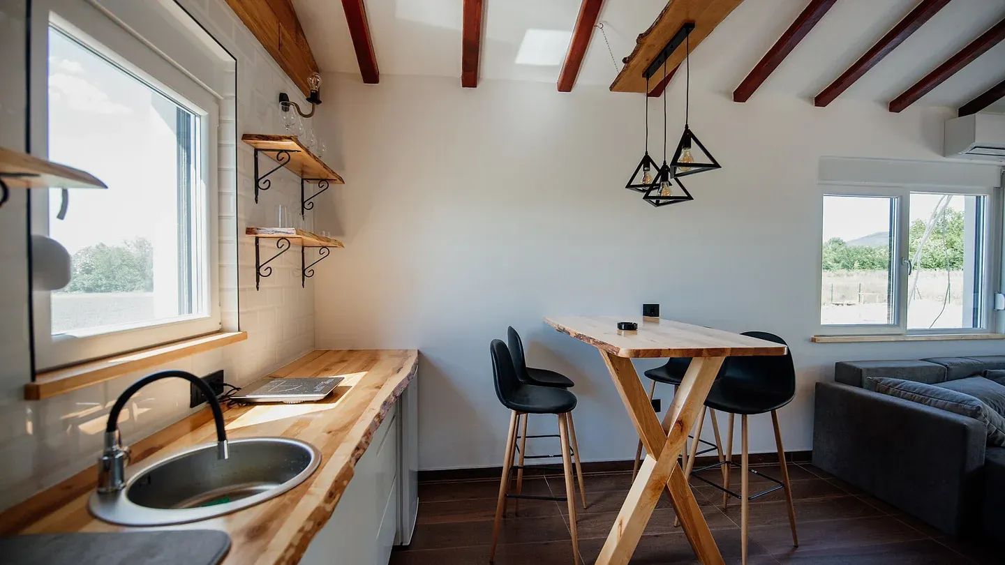 Cuisine japandi: comptoir de bois à chant naturel, absence d'armoires hautes, luminaires et chaises noir mat